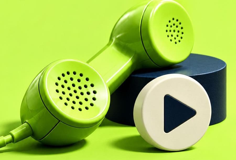 A lime telephone handset beside a play button on a navy podium